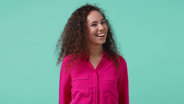 Confused young african american woman 20s in pink shirt posing isolated on blue turquoise background studio. People lifestyle concept. Pointing finger himself ask say who me no thanks i do not need it