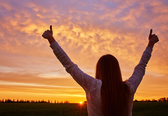 woman feeling victorious facing the beautiful sunset.