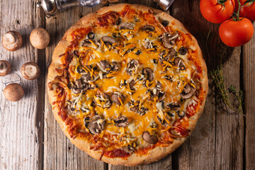 Italian pizza top view on wooden background. Cheese, olives and tomatoes ingredients. Background for culinary recipes.