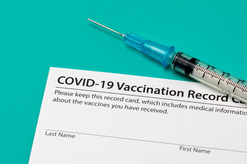 Covid-19 coronavirus vaccination record card with syringe and needle. Concept of vaccination, herd immunity and pandemic healthcare.