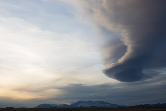 Scenic view of landscape against funnel clouds during sunset