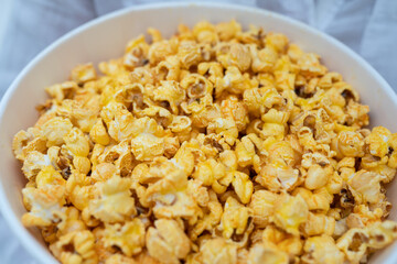 Close-up photo of a young sweet girl, who is holding a tube of popcorn in her hands.