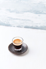 Coffee in glass cup on bright wooden background. Copy space.