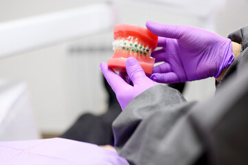 Fototapeta na wymiar Dentist showing to patient an orthodontics dental model, explaining to patient the orthodontics treatment in dental clinic. High quality photo