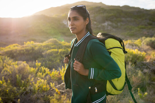 Mixed race woman wearing a backpack and hiking in mountains by the coast