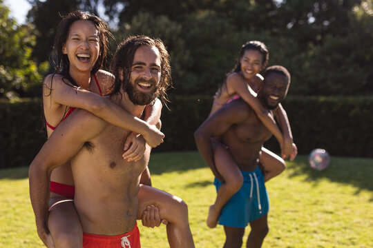 Diverse group of friends having fun and carrying on back at a pool party