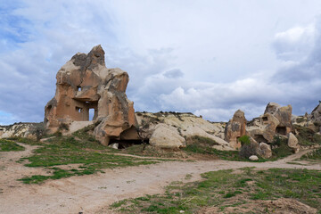 Walking road in a valley with fantastic rock formations near Goreme, Cappadocia. It is famous tourist destination in Turkey. Spring day, dramatic cloudy sky