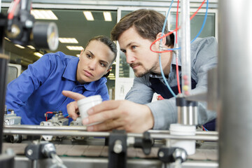 engineer training female apprentice on production machine