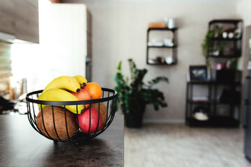 Fruits in fruit bowl on bar counter in stylish loft kitchen. Blurred background
