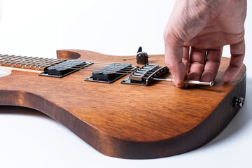 a man is tuning and adjusting a new electric guitar using measuring instruments - obrazy, fototapety, plakaty