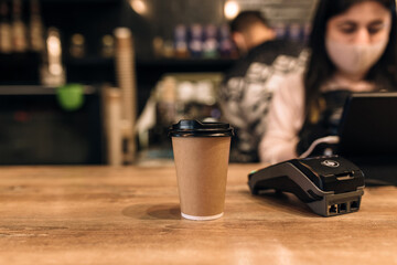 Buying a cup of coffee in a cafe, barista, NFC terminal. Blurred background