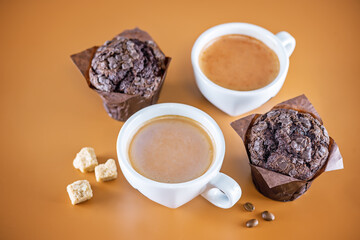 Cups of coffee with pastry on a brown background