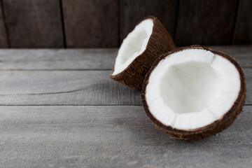 Broken coconuts on gray wooden background. White coconut pulp