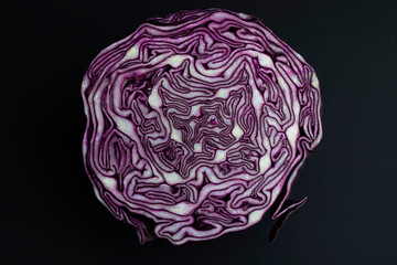 Red cabbage cut in half on a black background close-up.