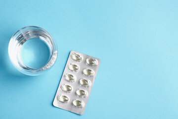 Glass of water and blister lay on a blue background.