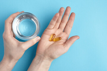 Top view of capsules on a hand on a blue background. Heap of pills - medical background
