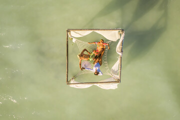 Aerial view of three people relaxing on a hammock along the beach of Villa Isabela, Puerto Plata, Dominican Republic.