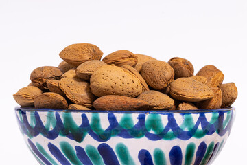 closeup of almonds in a ceramic bowl on a white background