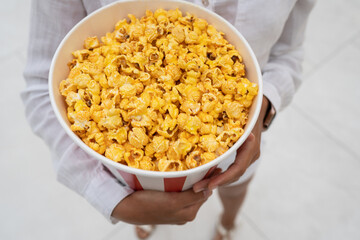 Close-up photo of a young sweet girl, who is holding a tube of popcorn in her hands.