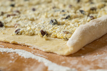 Roll out the dough stuffed with cottage cheese and raisins.