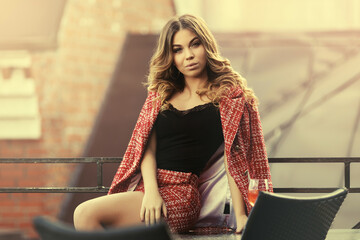 Young fashion woman in red tweed jacket and skirt suit at sidewalk cafe