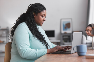 Side view portrait of curvy African American woman using laptop at desk and typing while enjoying work from home in minimal interior, copy space