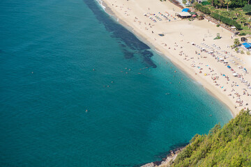 Fototapeta na wymiar View from above to the beach with people and turquoise sea. Holiday season vacation concept.