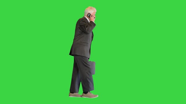 Senior businessman walking and making a call on a Green Screen, Chroma Key.