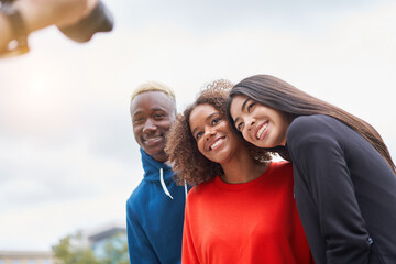 Obraz premium Multi ethnic friends outdoor on photo shooting looking at camera. Diverse group people Afro american asian spending time together Multiracial male female student meeting outdoors for photo