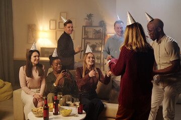 Happy young intercultural friends congratulating smiling girl on her birthday