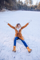 woman sitting in the snow. Woman is having fun outside in the snow. Woman with brown coat on a...