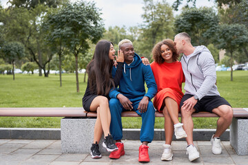 Multi-ethnic group teenage friends. African-american asian caucasian student spending time together Multiracial friendship Happy smiling People dressed colorful sportswear sitting bench park outdoor