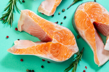 Fresh raw salmon steak with spices and herbs on light blue background close up. Sea food concept.