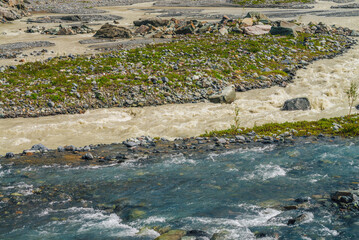 Sunny alpine landscape with confluence of two various mountain rivers. Beautiful clear creek flows...