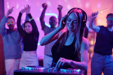 Pretty girl with long blond hair touching headphones while mixing sounds