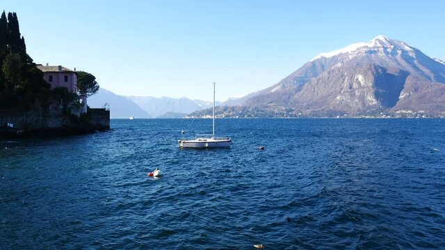 A small boat floating over the blue waters of Lake Como, Italy, in the lovely village of Varenna, close to Bellagio and Menaggio.