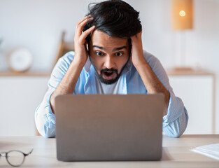 Deadline Stress. Arab man looking at laptop screen, touching head in shock