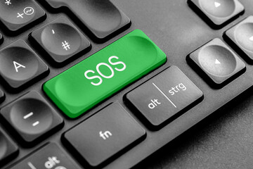 grüne "SOS" Taste auf einer dunklen Tastatur