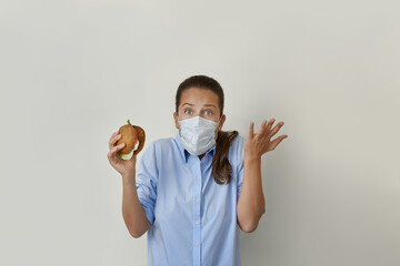 Hungry pretty woman in protective face mask tries to eat a vegan burger stock photo