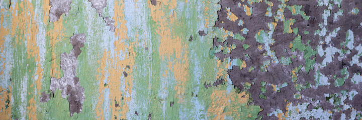 Peeling paint on the wall. Panorama of a concrete wall with old cracked flaking paint. Weathered rough painted surface with patterns of cracks and peeling. Wide panoramic texture for design background