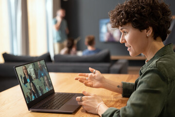 Side view of contemporary businesswoman talking to colleagues in video chat