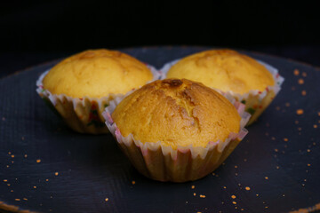 Three cupcakes on a plate on a black background