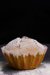 cupcake in powdered sugar on a plate on a black background