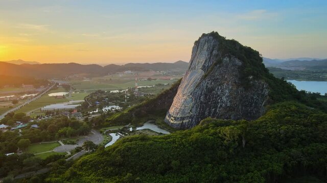 4k Fast Wide pan around Buddha Mountain in Pattaya at stunning Sunrise. Drone shot: image of Buddha engraved with gold into the hill in Khao Chi Chan, Chonburi, Thailand. Cinematic thai attractions.