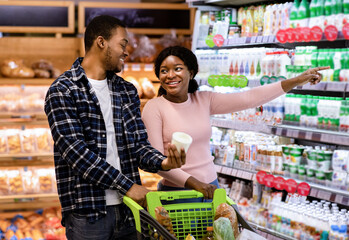 Happy millennial black couple choosing dairy products at shopping mall