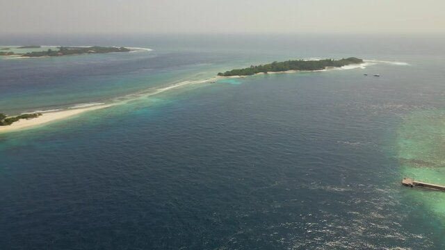 Aerial shot panning over an atoll in the maldives