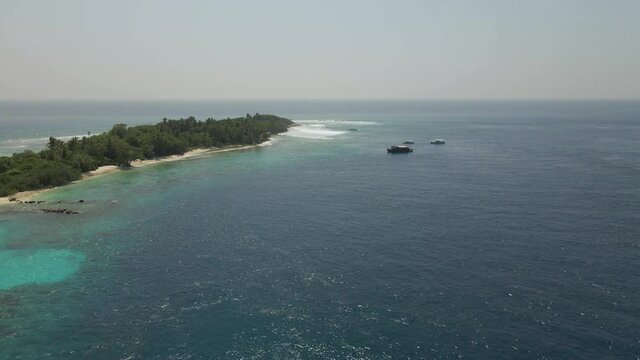 Aerial Drone pans down over boats in the maldives islands