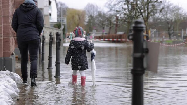 Mother And Daughter Walk On The Flooded Sidewalk In Eltville Town In Germany. wide shot
