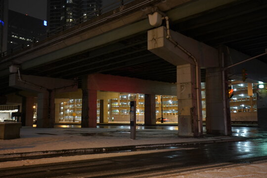 Urban city bridge underpass at night time during rainy day with reflection on the streets and big intersection
