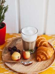 delicious latte coffee in a glass and a croissant and fruits